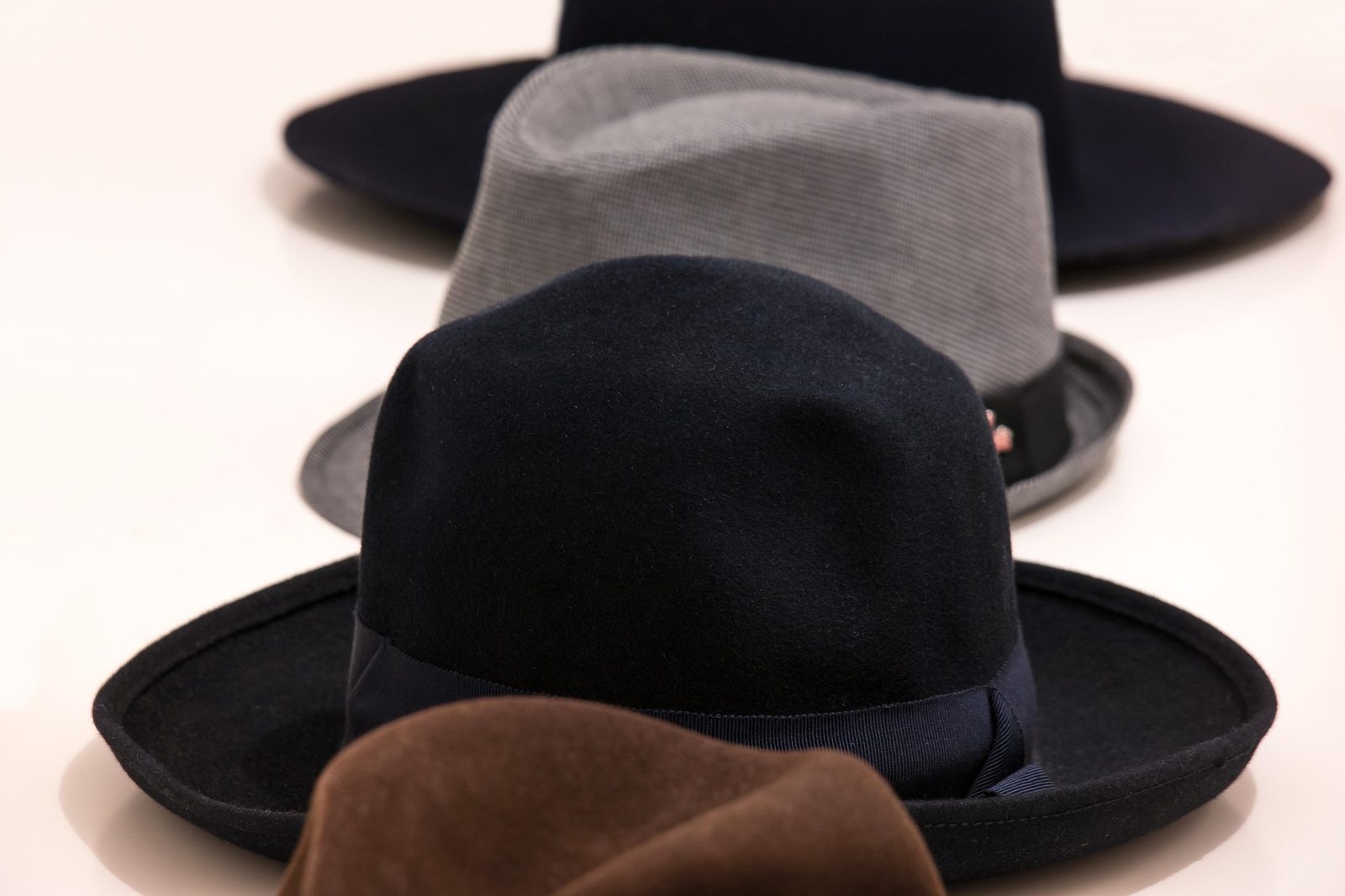 Felt fedoras in navy, grey and brown lined up on a counter
