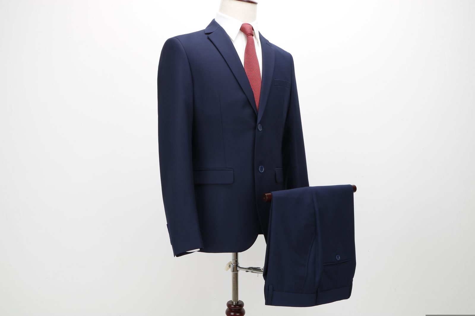 Navy two button suit with a red tie, styled on a tailor's form